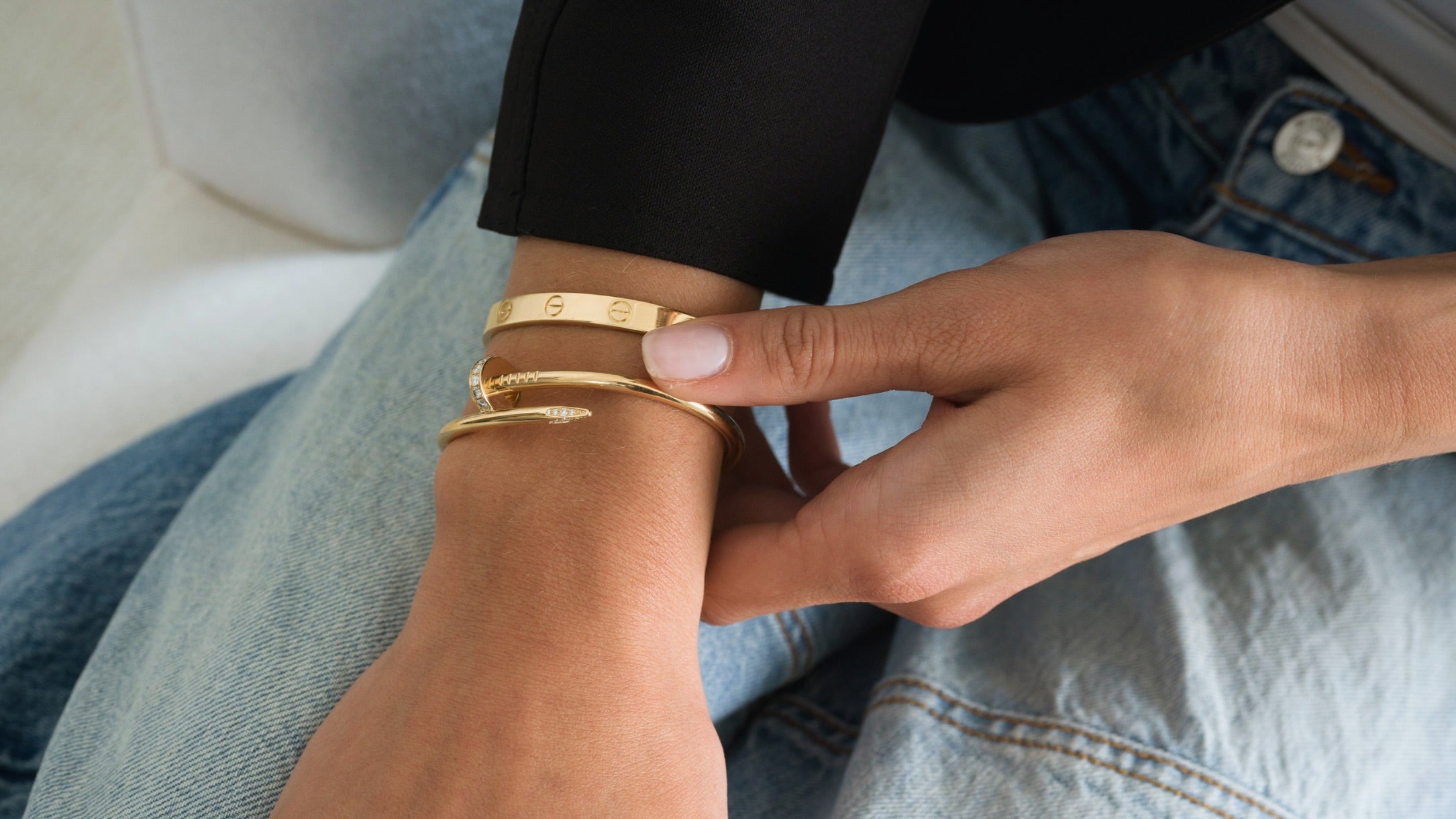 Two gold Cartier bracelets worn on woman's wrist