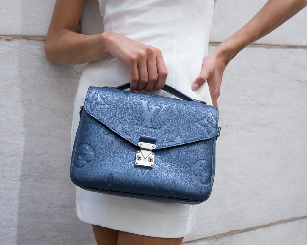 Model holding a metallic blue Louis Vuitton bag
